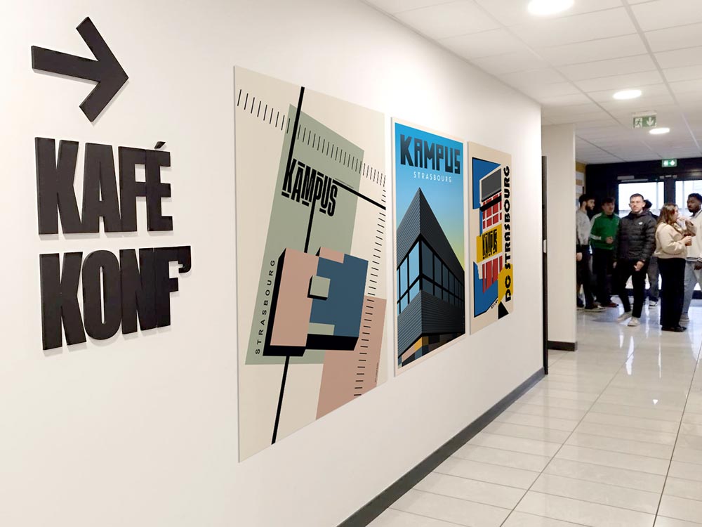 Un couloir du Digital Campus Strasbourg avec des affiches au style vintage sur le mur, inspirées du design graphique, et un groupe d'étudiants en arrière-plan